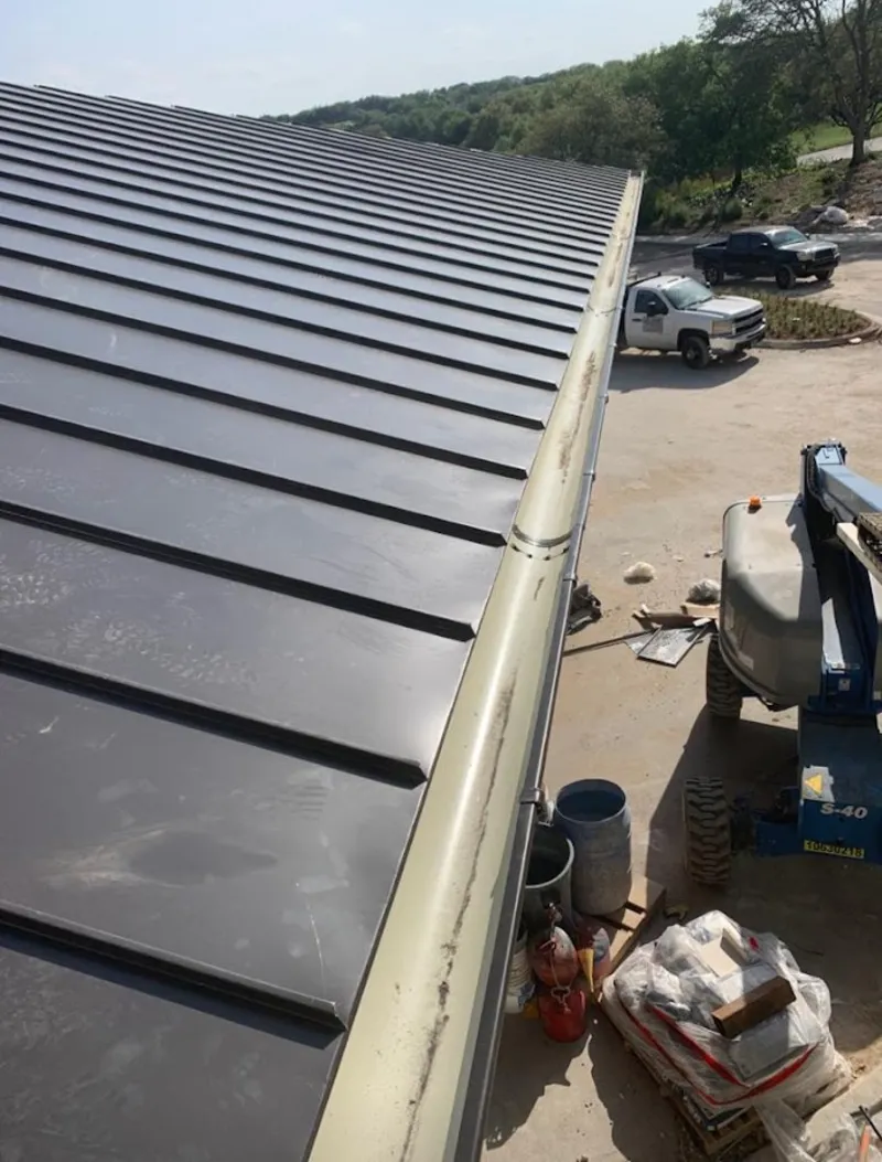 Standing seam panel and gutter detail on a metal roofing jobsite in Munford